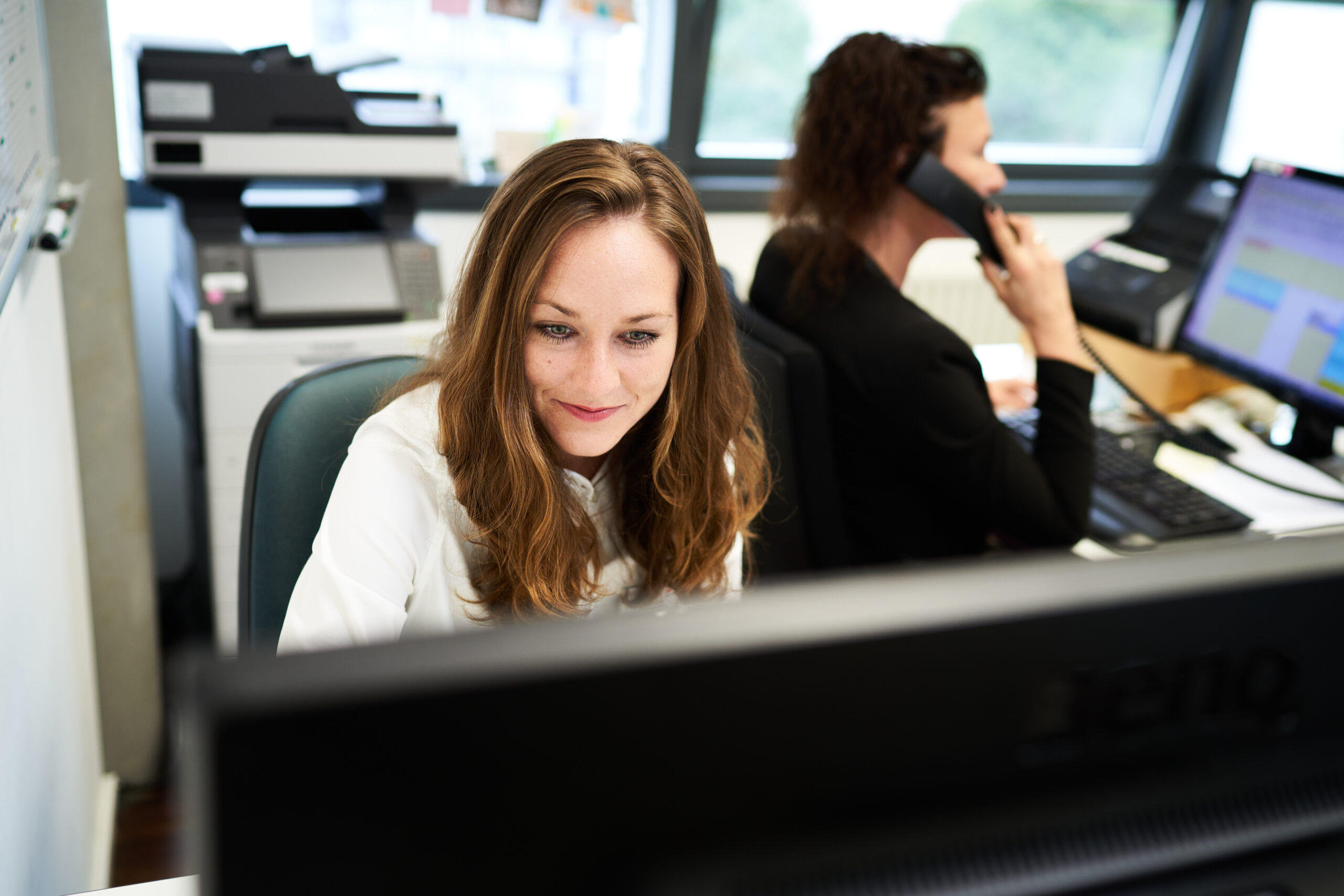 Zwei Mitarbeiterinnen an ihren Computerarbeitsplätzen