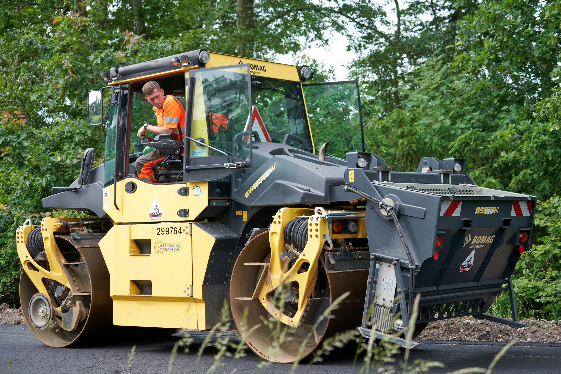 Mitarbeiter bei Straßenbauarbeiten mit Baumaschine