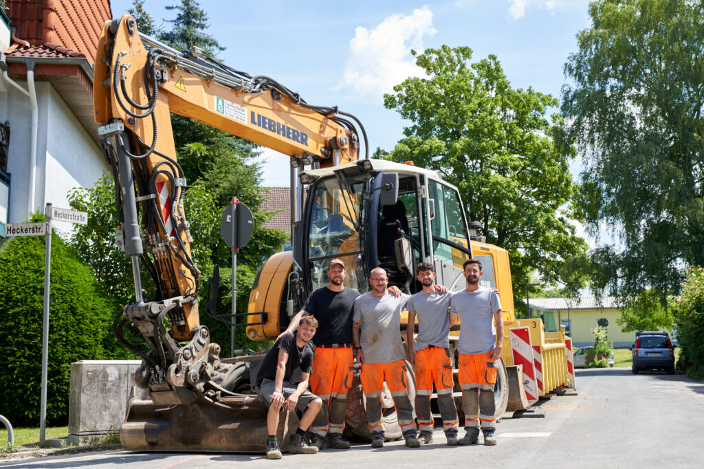 Straßenbauer-Team bei Tiefbauarbeiten mit Baumaschinen